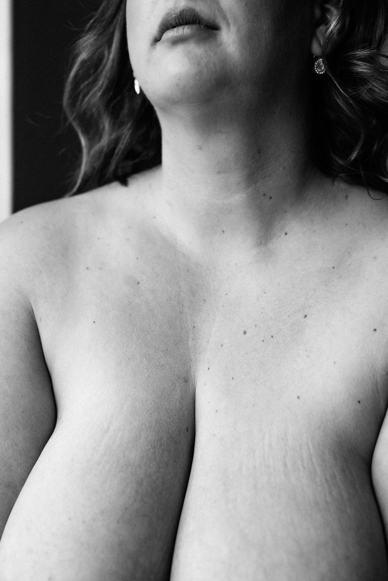A black and white photograph, cropped to the chest and neck. Little freckles look like constellations across het chest.