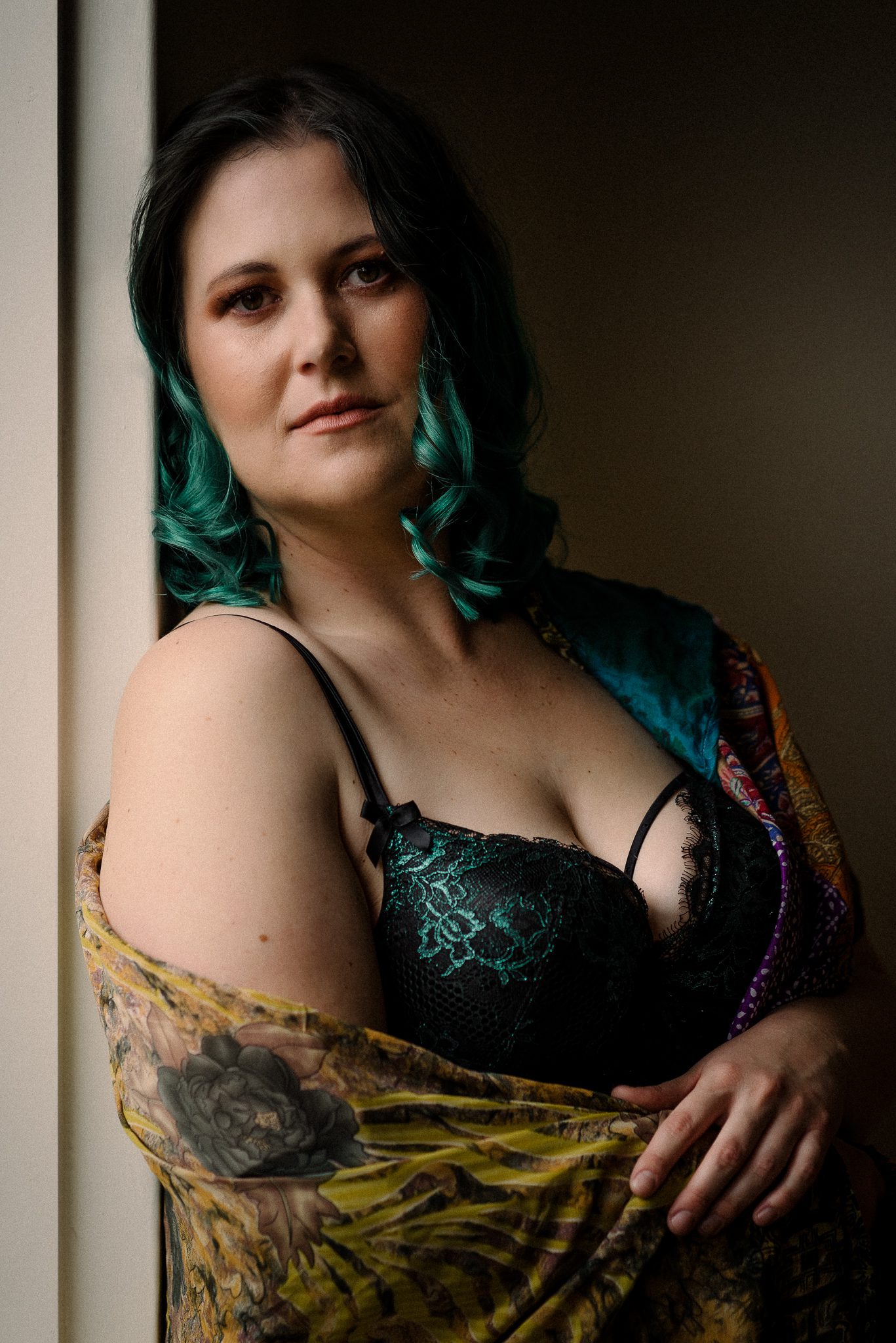 Boudoir portrait of a lady with green hair and bra, wrapped in a bright shawl