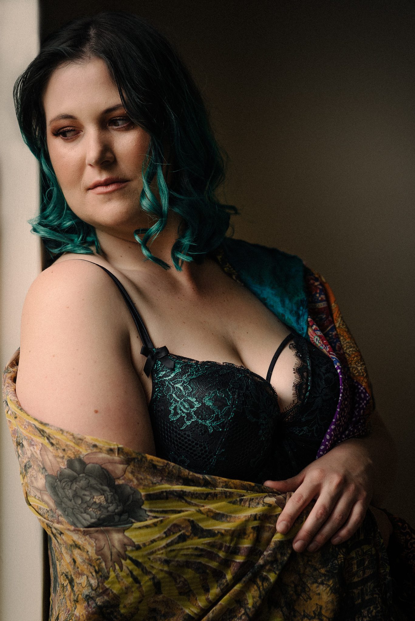 Boudoir portrait of a lady with green hair and bra, wrapped in a bright shawl