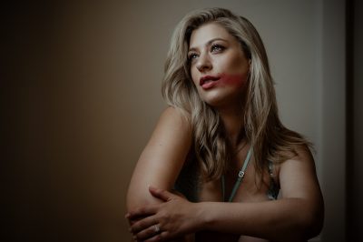 A portrait of a lady with turquoise lingerie and red lipstick smeared across her cheek taken during a boudoir shoot in Adelaide.