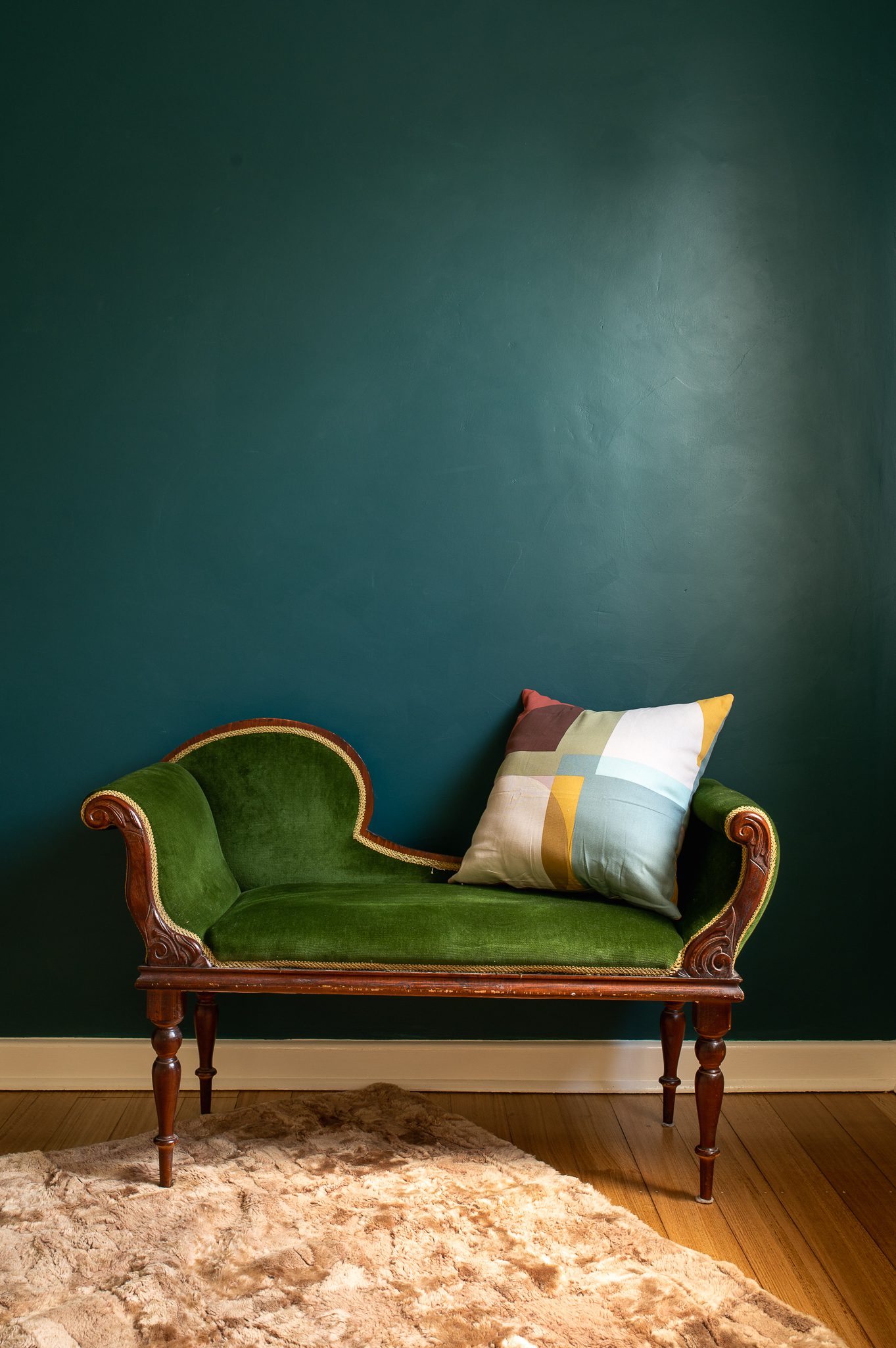 A close up of a vintage Victorian love seat with green velvet upholstery.